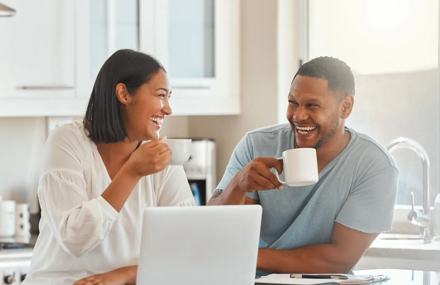 Shot of a couple drinking coffee while using a laptop in the kitchen at home stock photo