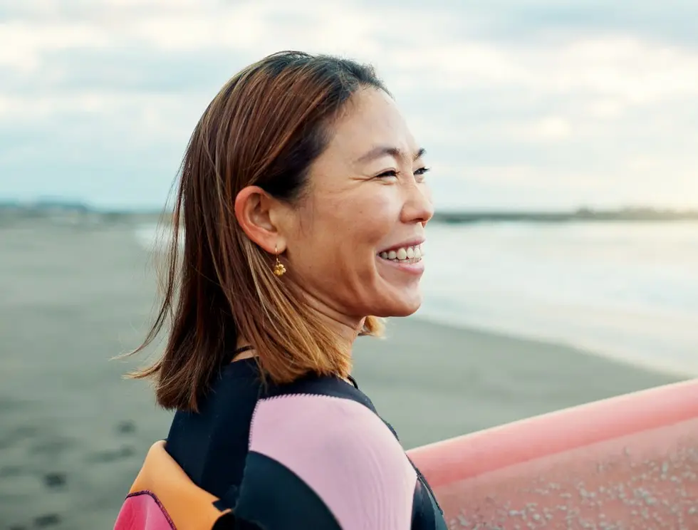 Happy, woman and surfer thinking at beach, sea and ocean for summer holiday, travel adventure or hobby. Japanese lady smile with surfing board for water sports, freedom or relax for tropical vacation