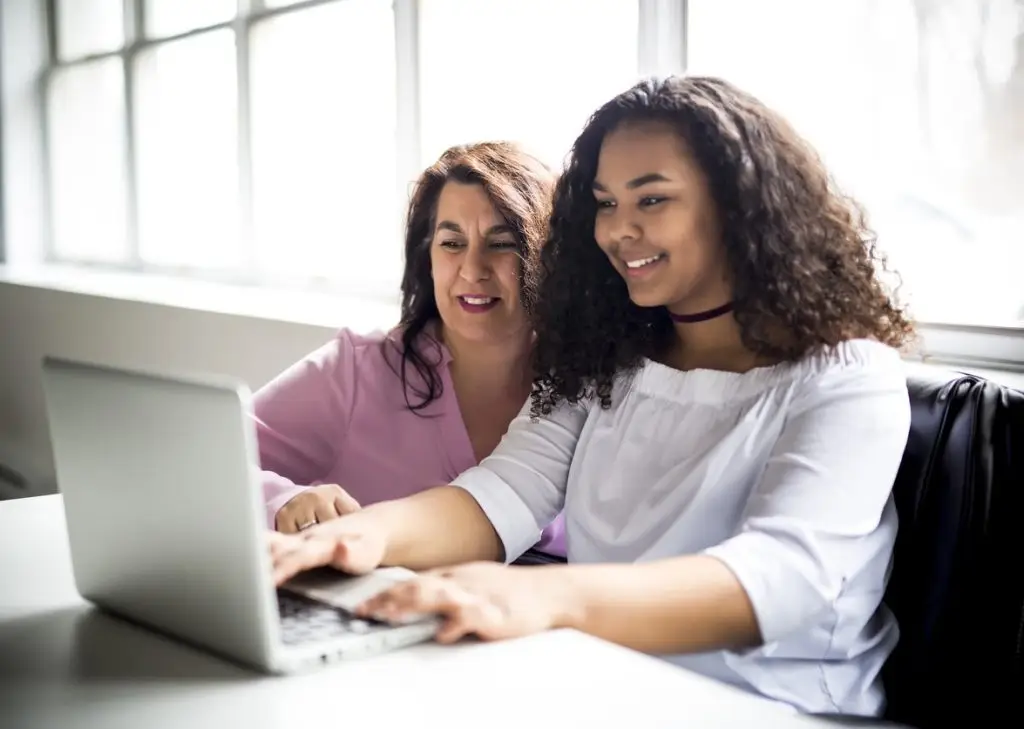 A Mother And Teenage Daughter Looking At Laptop Together